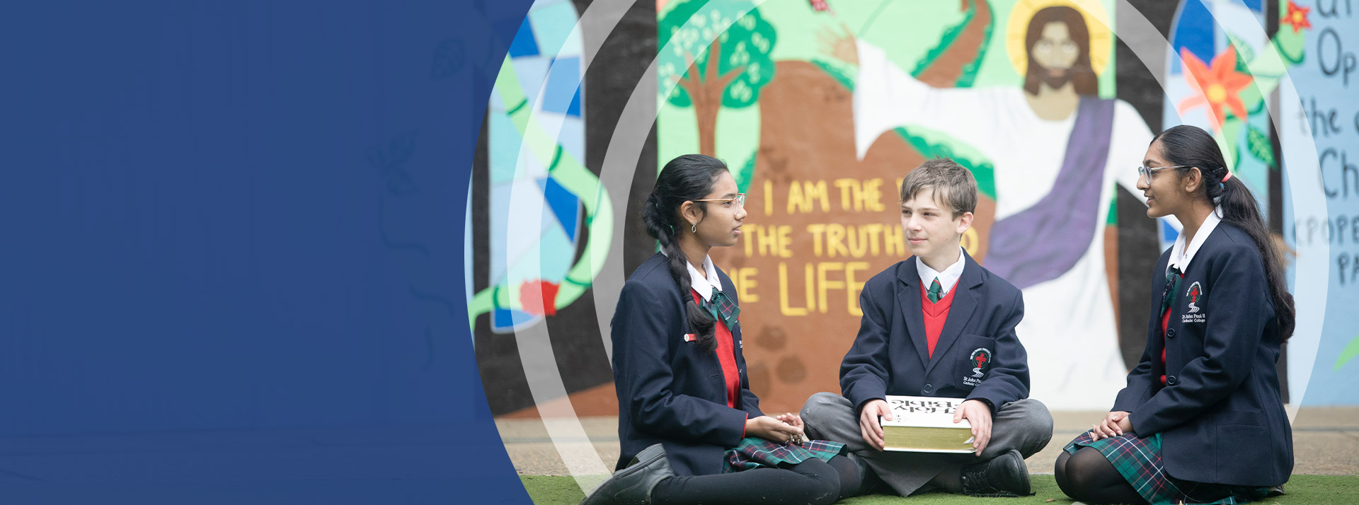 Students sitting together in front of a mural at St John Paul II Catholic College Schofields