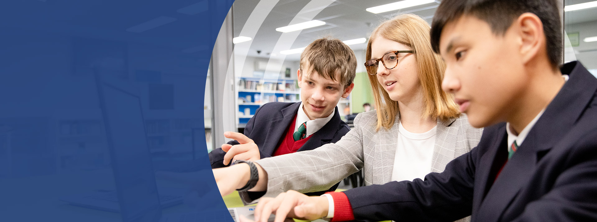 Teacher working with her students on a laptop at St John Paul II Catholic College Schofields and Nirimba