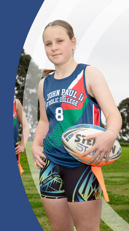The girls football team standing on the school oval at St John Paul II Catholic College Schofields