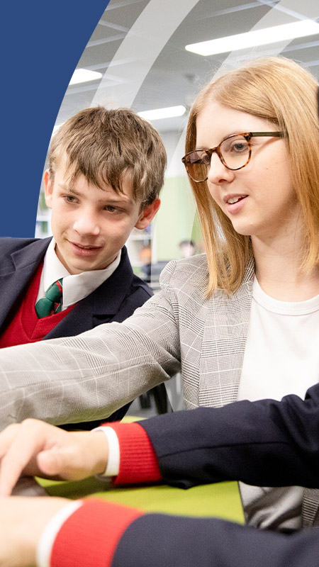 Teacher working with her students on a laptop at St John Paul II Catholic College Schofields and Nirimba