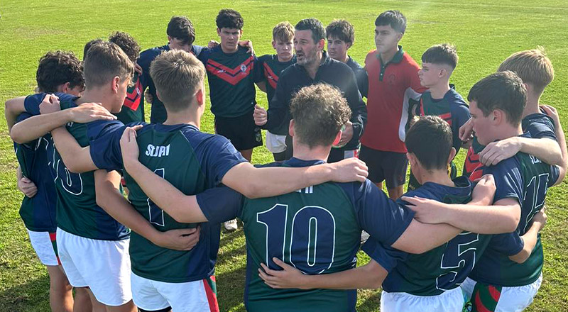 The St John Paul II Catholic College Schofields boys football team in a huddle before a game