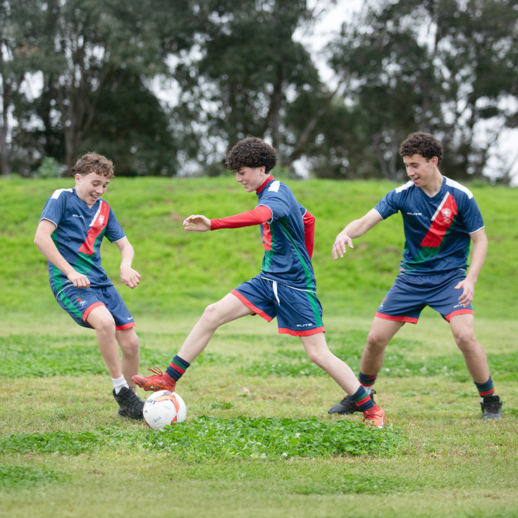 Students playing soccer together on the school oval at St John Paul II Catholic College Schofields