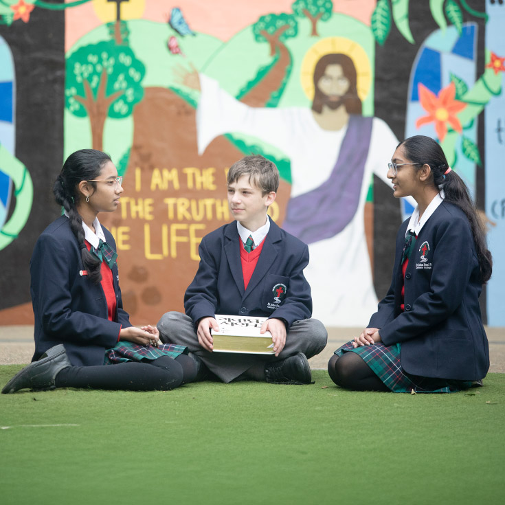 Students sitting together in front of a mural at St John Paul II Catholic College Schofields